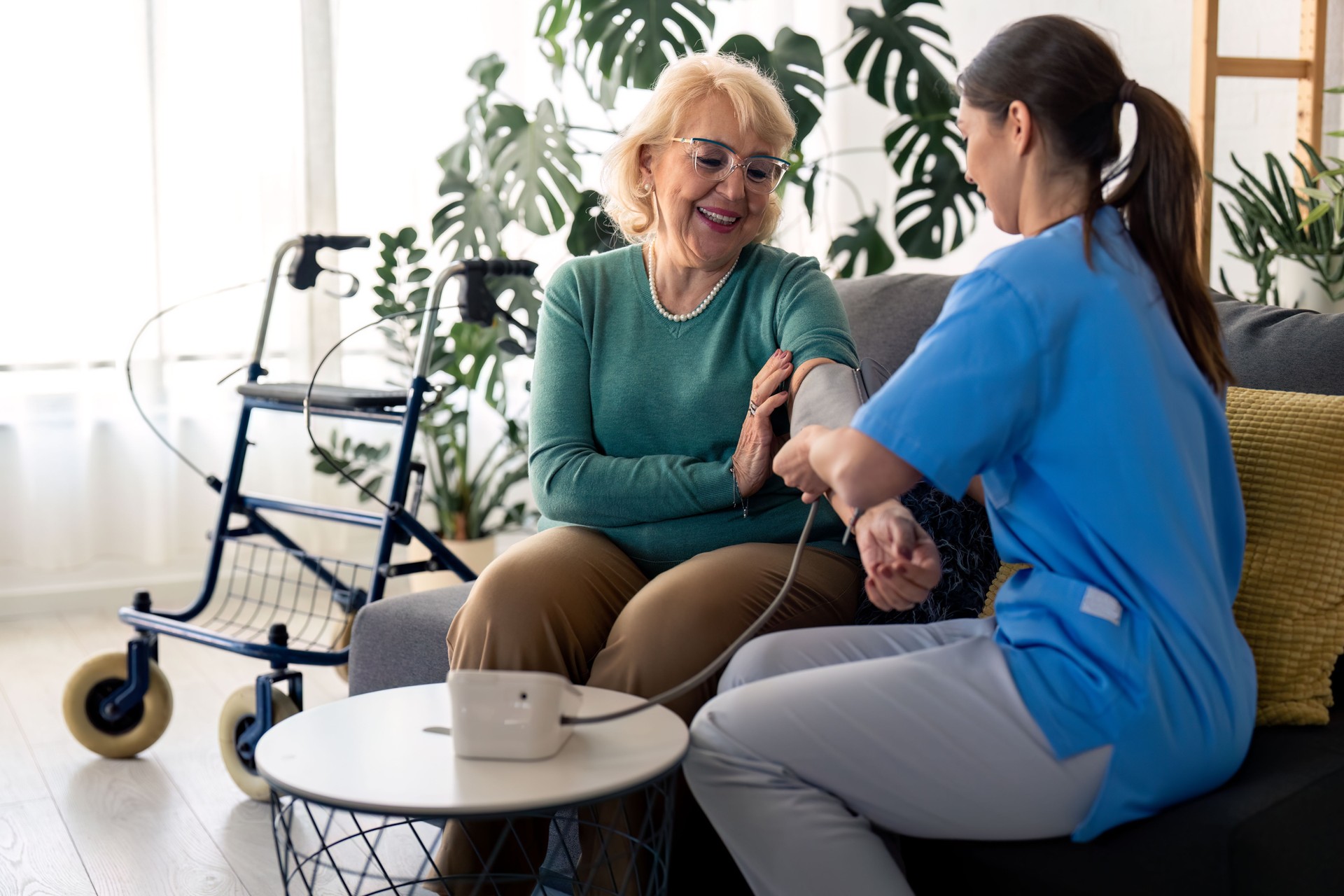 Female nurse assisting senior woman to measure blood pressure